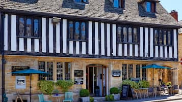 A traditional Tudor-style building with a stone facade, multiple windows, and a welcoming entrance.