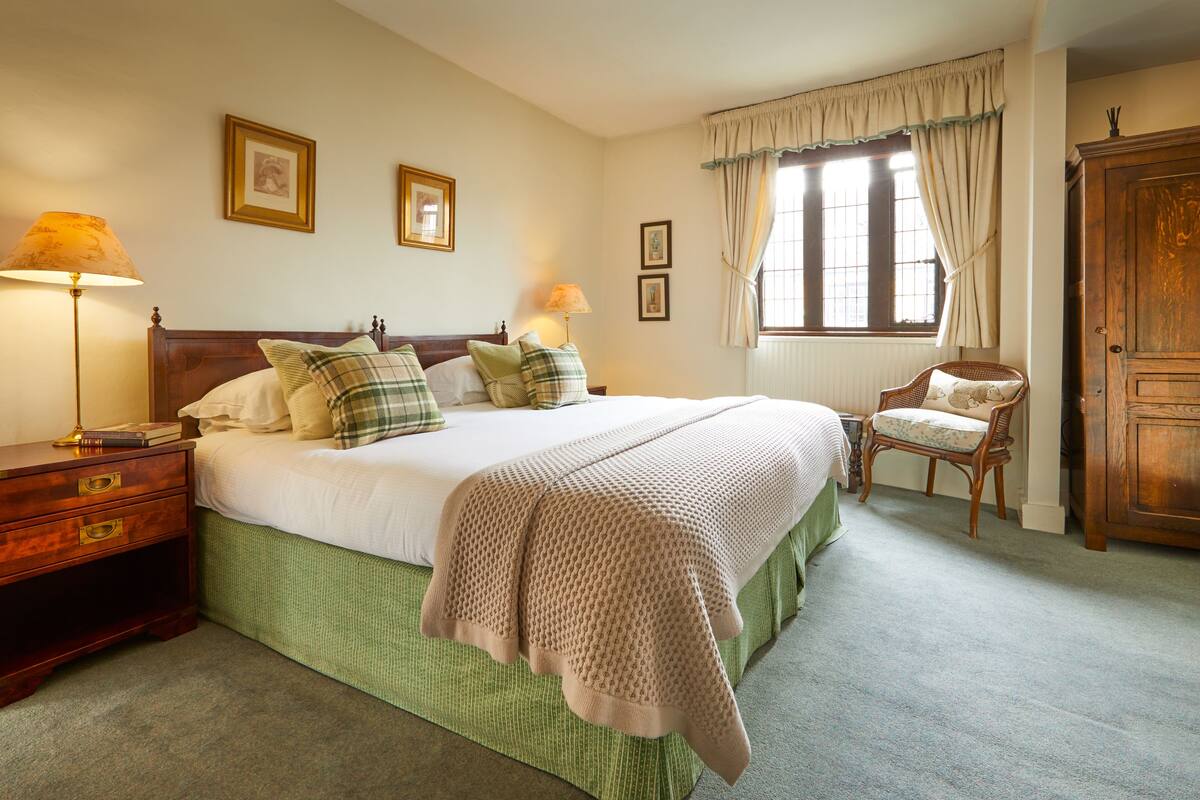 A bedroom with a large bed, two bedside tables, a chair, and a wardrobe.