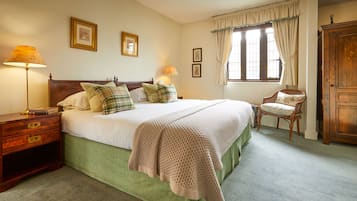 A bedroom with a large bed, two bedside tables, a chair, and a wardrobe.