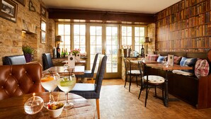 A cozy room with a fireplace, a bookshelf, and a dining area with a table and chairs. - Burford House (Burford)