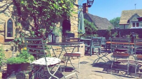 An outdoor seating area with stone walls and a rustic stone building in the background.