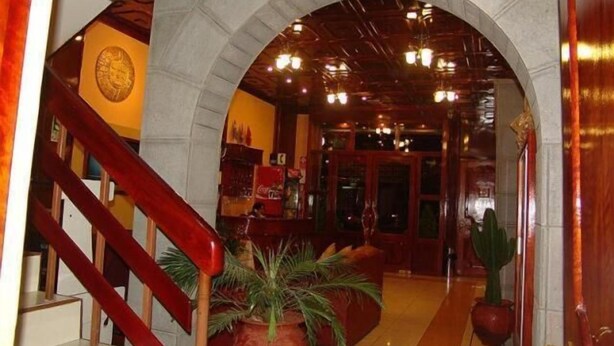 A lobby with a stone archway, a staircase with red railings, and potted plants. - Inkayra Hotel (Cusco)