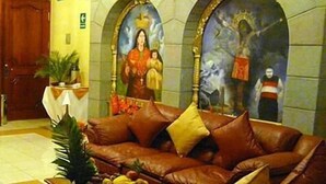 A lobby with a brown leather sofa, a fruit basket, and two religious paintings on the wall. - Inkayra Hotel (Cusco)