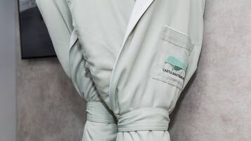 A person wearing a light-colored robe with a pocket that has a logo and text.