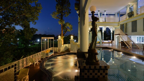 Zona de piscina con estatua, escaleras y un balcón con barandillas.