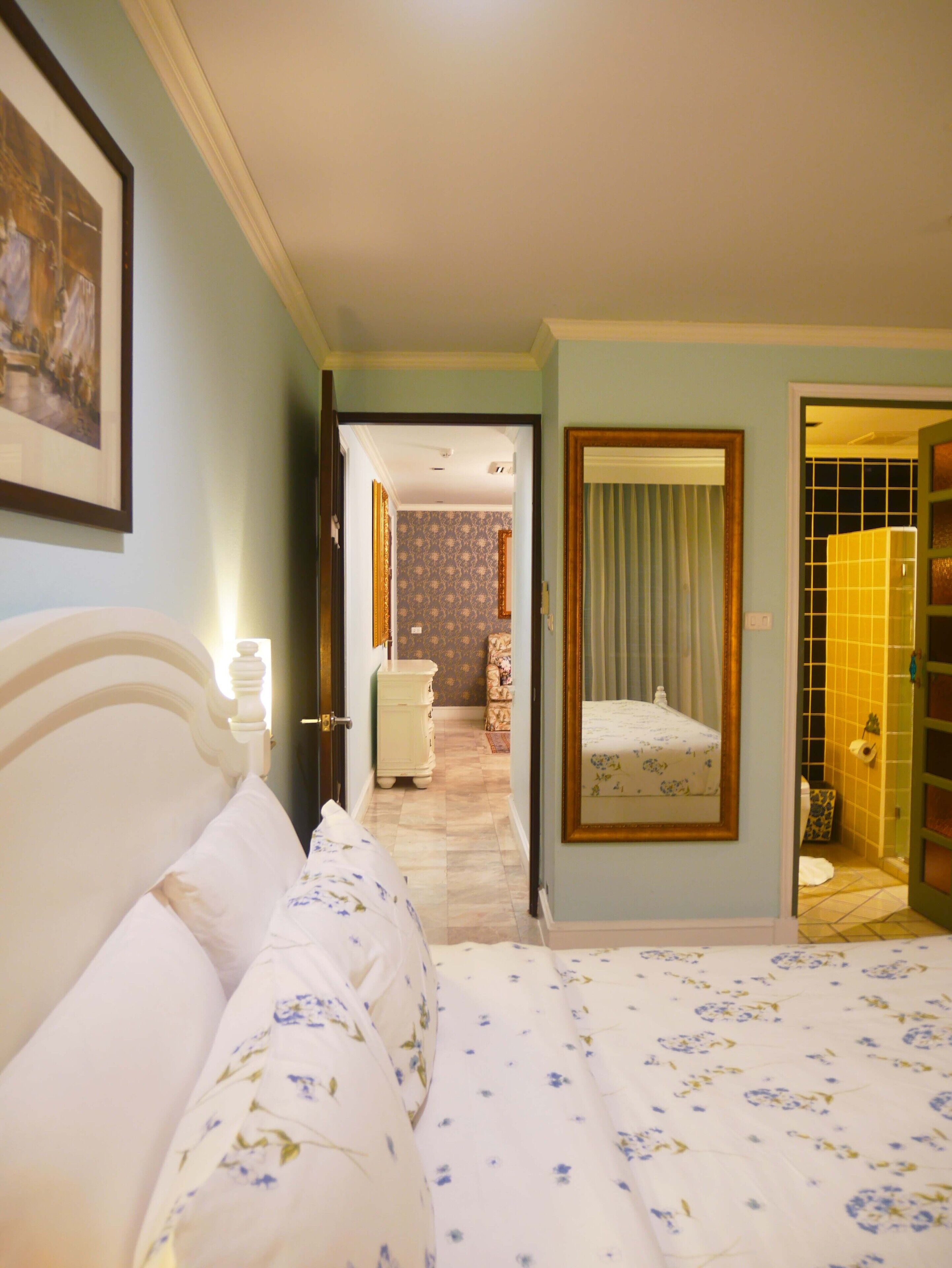 A hotel room with a bed, a dresser, a mirror, and a bathroom visible through an open door.