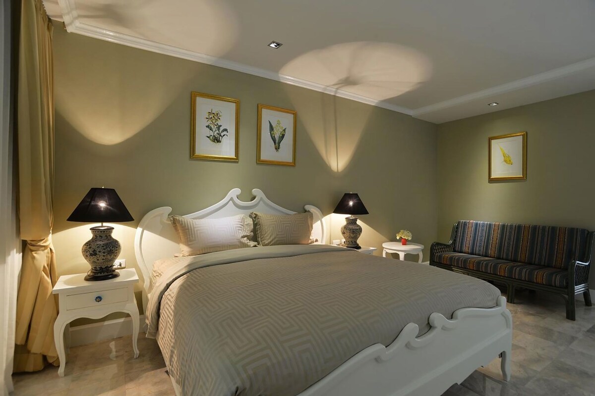 Une chambre à coucher comprenant un lit, deux tables de chevet, une commode, une chaise et un canapé.