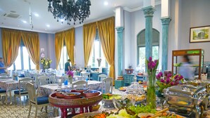 Un comedor de hotel con varias mesas, sillas y un bufé con diversos platos.