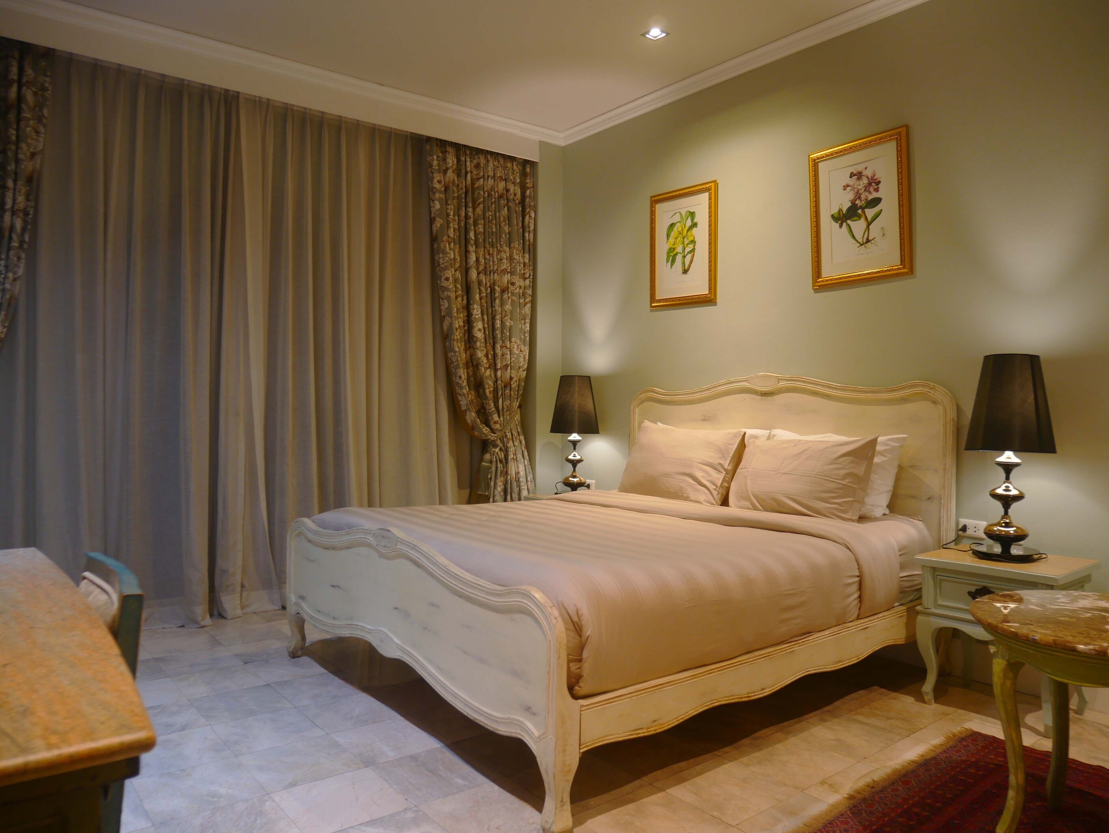 Un dormitorio con una cama, dos lámparas de noche, una mesita y una silla.