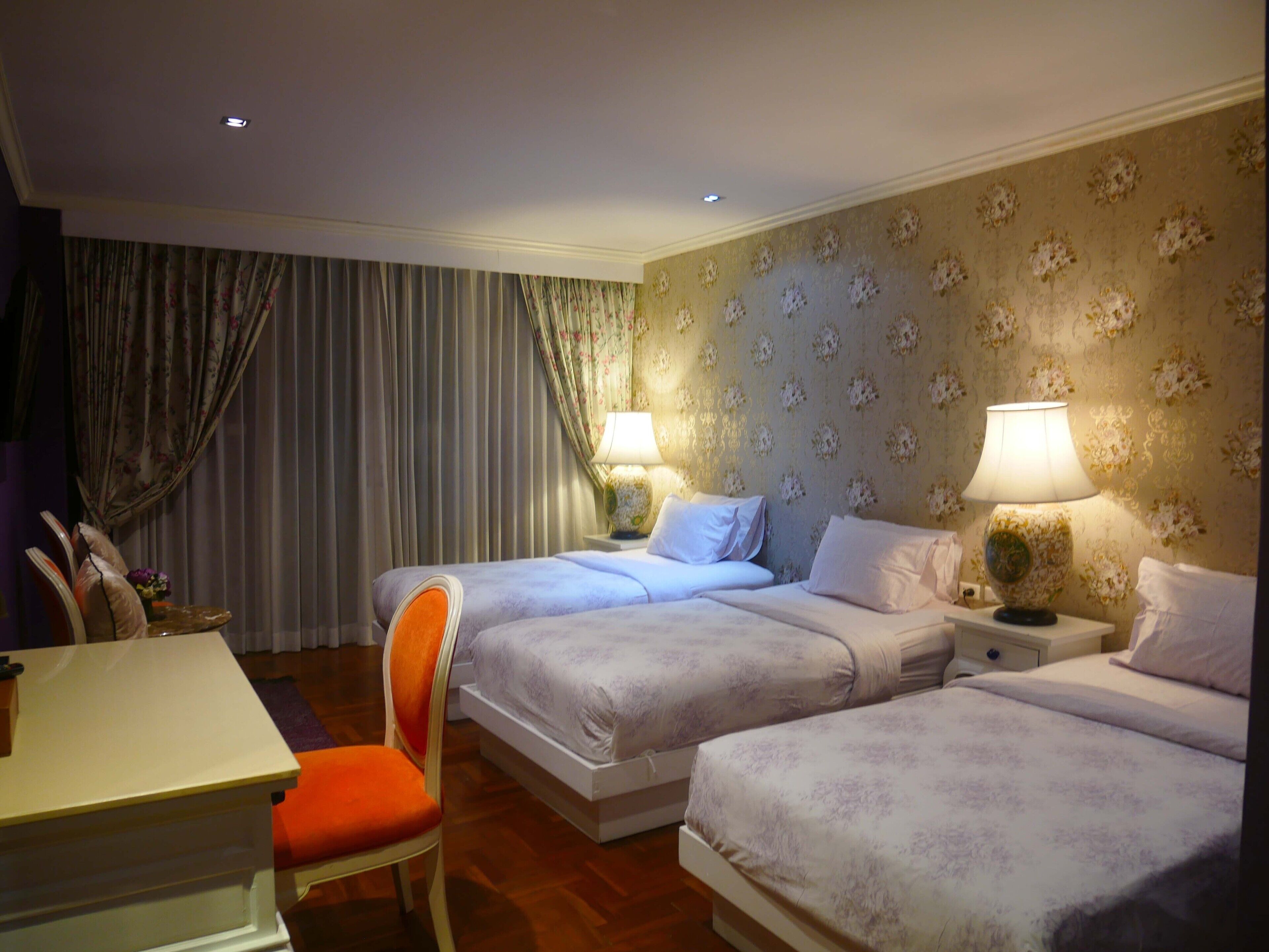 A hotel room with two beds, a desk, and a chair.