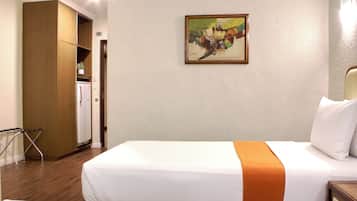 Una habitación de hotel con una cama, un cuadro en la pared y una zona de kitchenette.