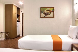Una habitación de hotel con una cama, un cuadro en la pared y una zona de kitchenette.