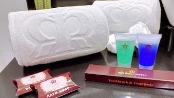 A bathroom with two white towels, a toothbrush, toothpaste, and a bar of soap.