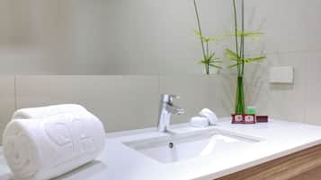 A bathroom with a white sink, a towel, a mirror, and a bamboo plant.