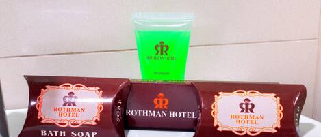 Tres paquetes de jabón de baño Rothman Hotel y un tubo de champú verde.