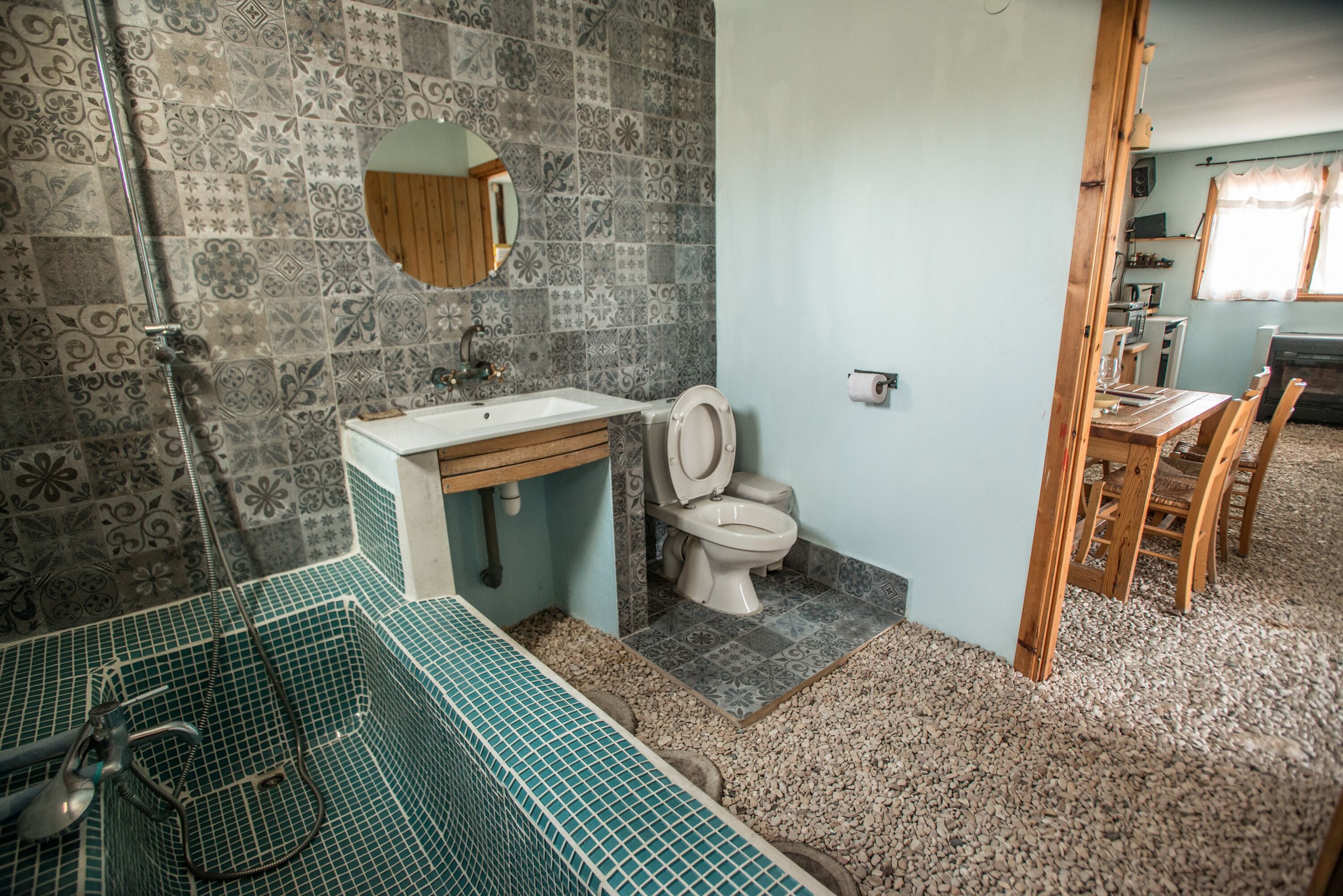 A bathroom with patterned tiles, a sink, a toilet, and a shower.