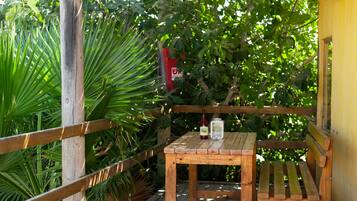 Eine Holzterrasse mit Tisch und Bank, umgeben von üppigem Grün.