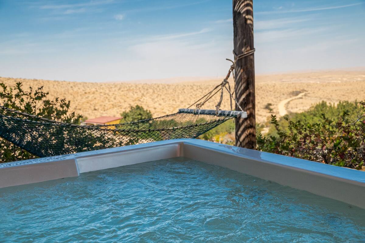 Un jacuzzi con una hamaca, rodeado por un paisaje desértico.