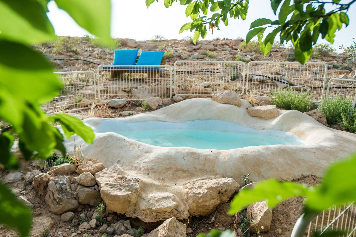 Una piscina natural rodeada de rocas y una cerca de metal.