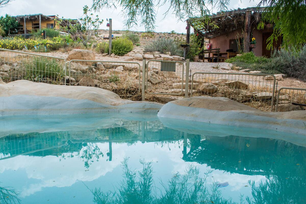 Una piscina de agua cristalina, rodeada de rocas y vegetación escasa.