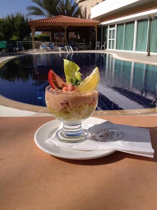 A dessert on a white plate with a pool and a building in the background.