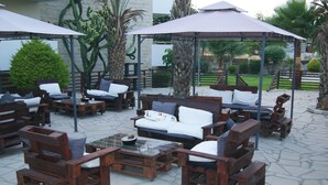 An outdoor seating area with wooden furniture and umbrellas. - Moniatis Hotel (Limassol)