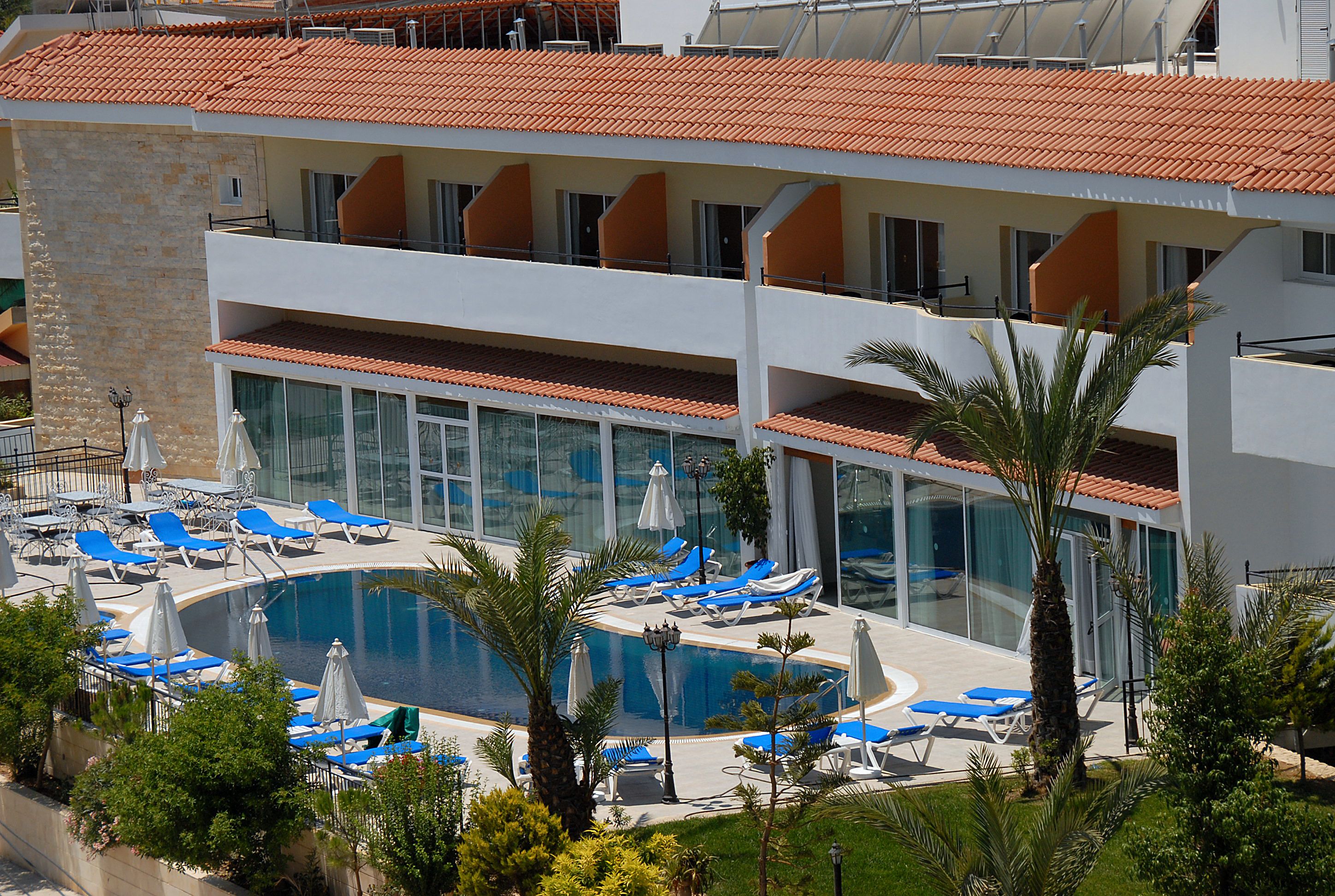 Un hôtel doté d’une piscine, de chaises longues et d’une façade en pierre.
