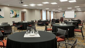 A conference room with multiple tables, chairs, and a projector screen.