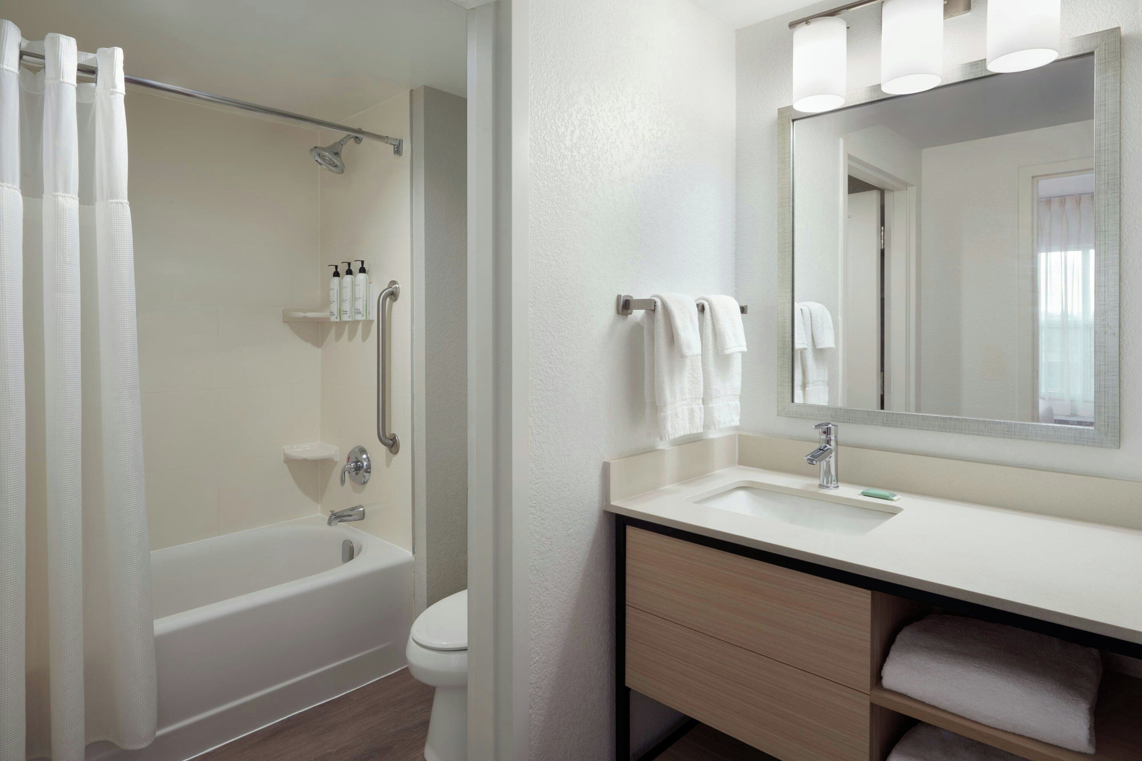 A bathroom with a bathtub, toilet, sink, and a mirror.