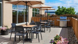 An outdoor patio with tables, chairs, and umbrellas. - TownePlace Suites by Marriott Thunder Bay (Thunder Bay)