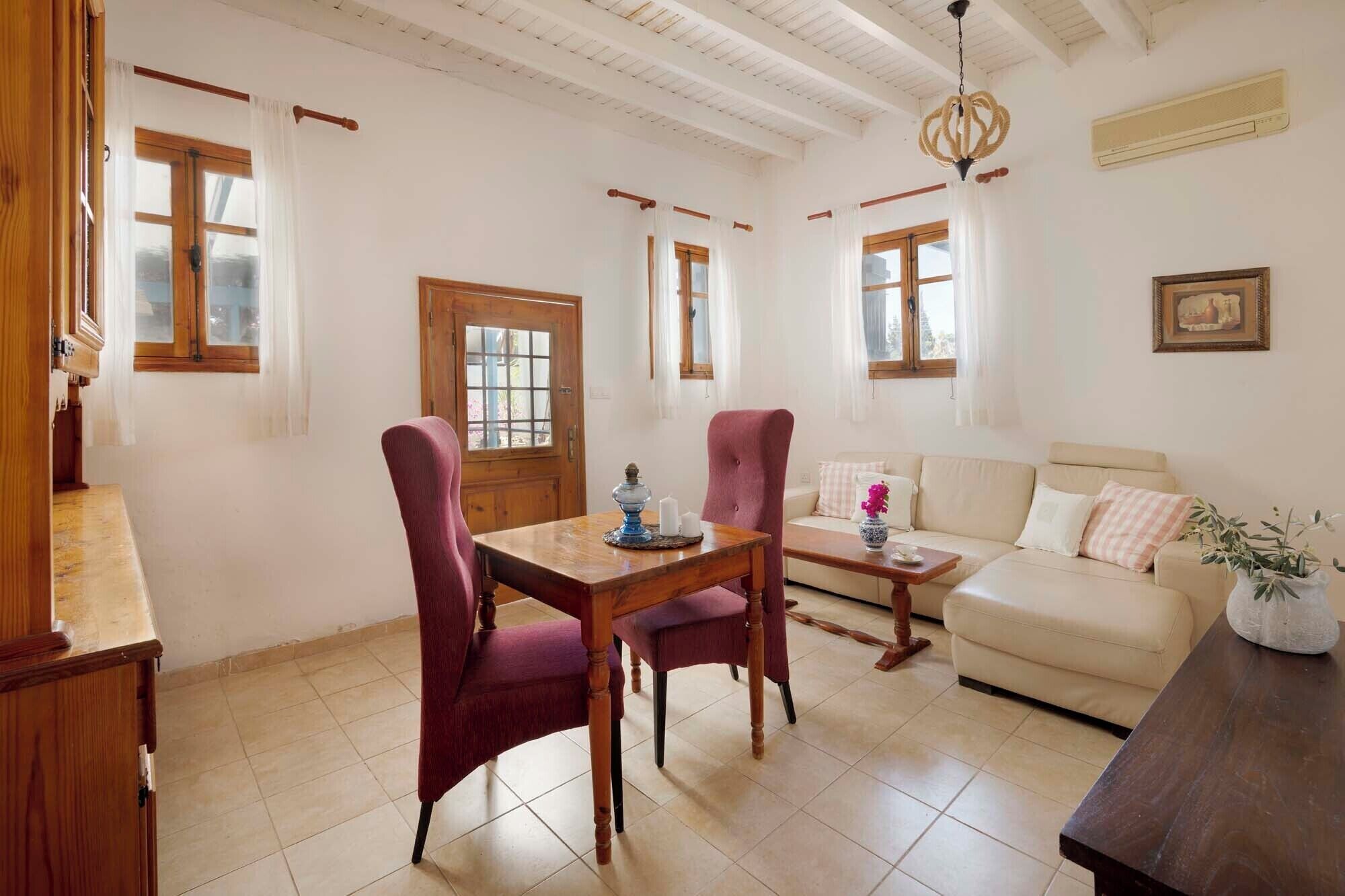 A dining area with a wooden table and chairs, a sofa, and a chandelier.