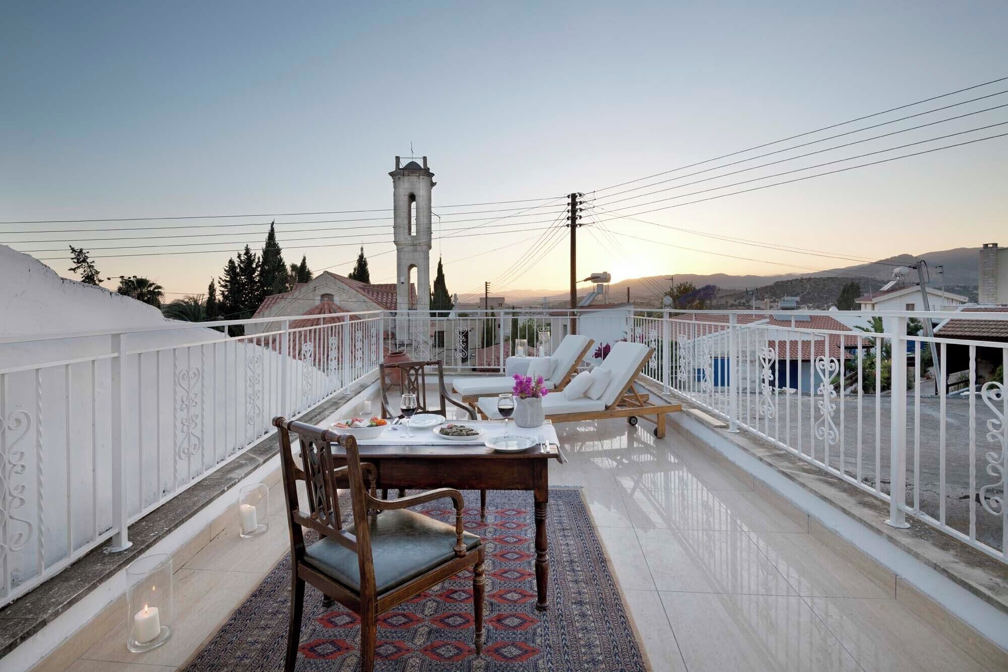 Une terrasse sur le toit, avec une table à manger, des chaises et une vue sur une tour et des bâtiments en arrière-plan.