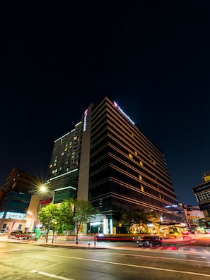 A modern hotel with a prominent sign, multiple floors, and a well-lit facade.