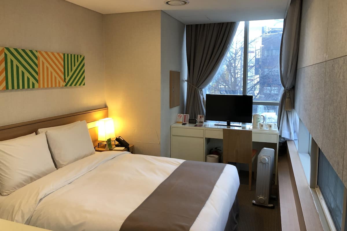 Habitación de hotel con cama, escritorio y ventana.