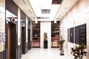 A modern lobby with glass doors, a central plant, and artwork on the walls. - Tmark Hotel Myeongdong (Seoul)