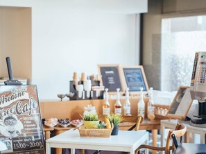 A cafe interior with a menu board, coffee machine, and a plant display. - Hotel AreaOne Miyazaki (Miyazaki)