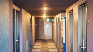 Un pasillo de hotel con piso a cuadros, puertas a ambos lados y un candelabro central.