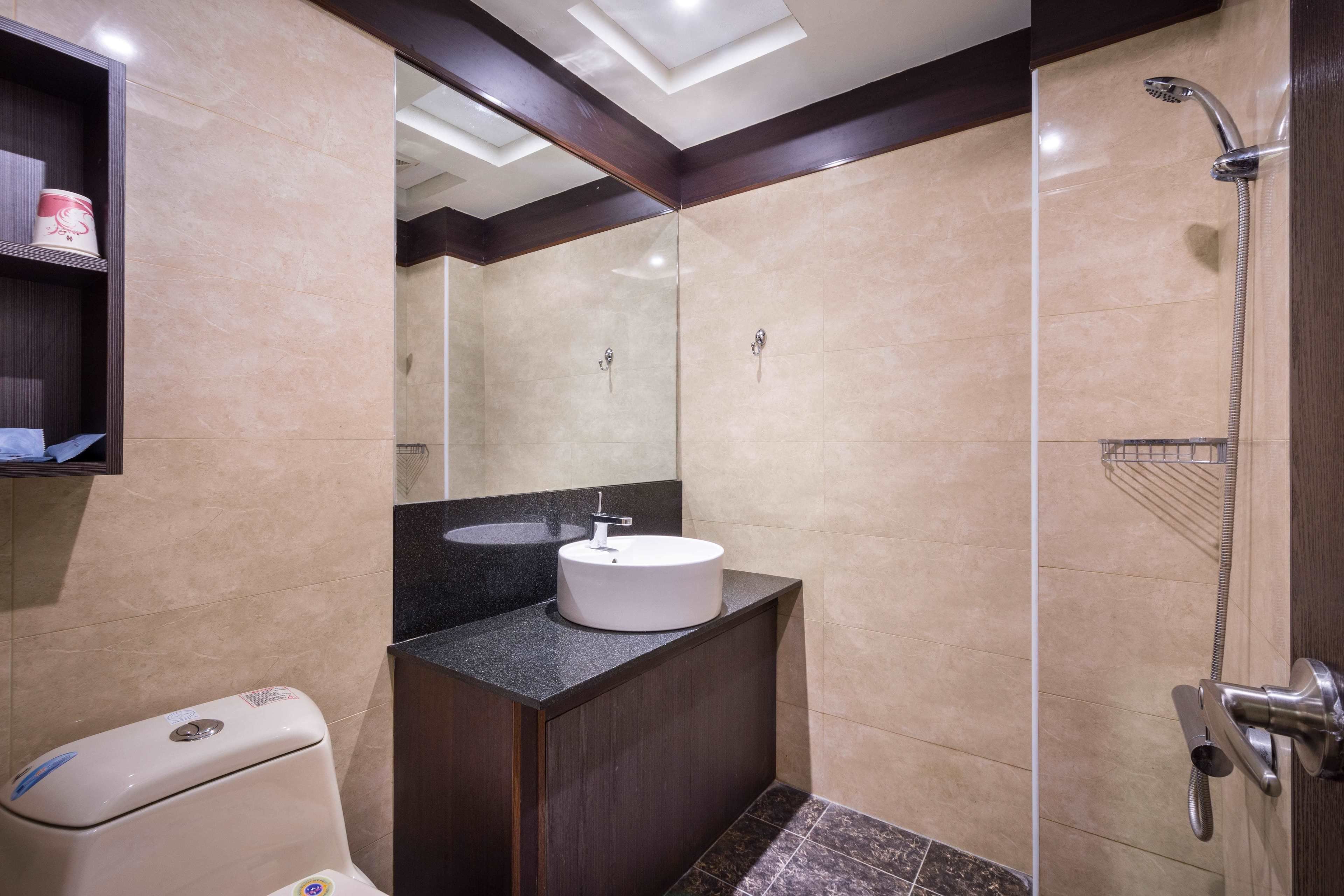 A modern bathroom with a round sink, a shower, and a toilet.