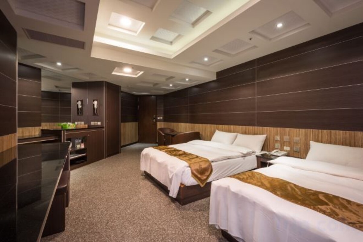 A hotel room with two beds, a desk, and a mirror.