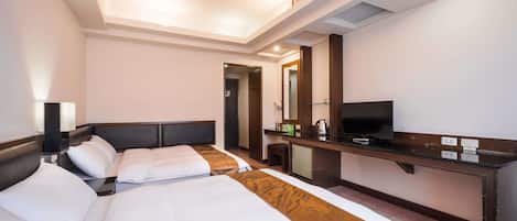 A hotel room with two beds, a desk with a TV, and a mirror.