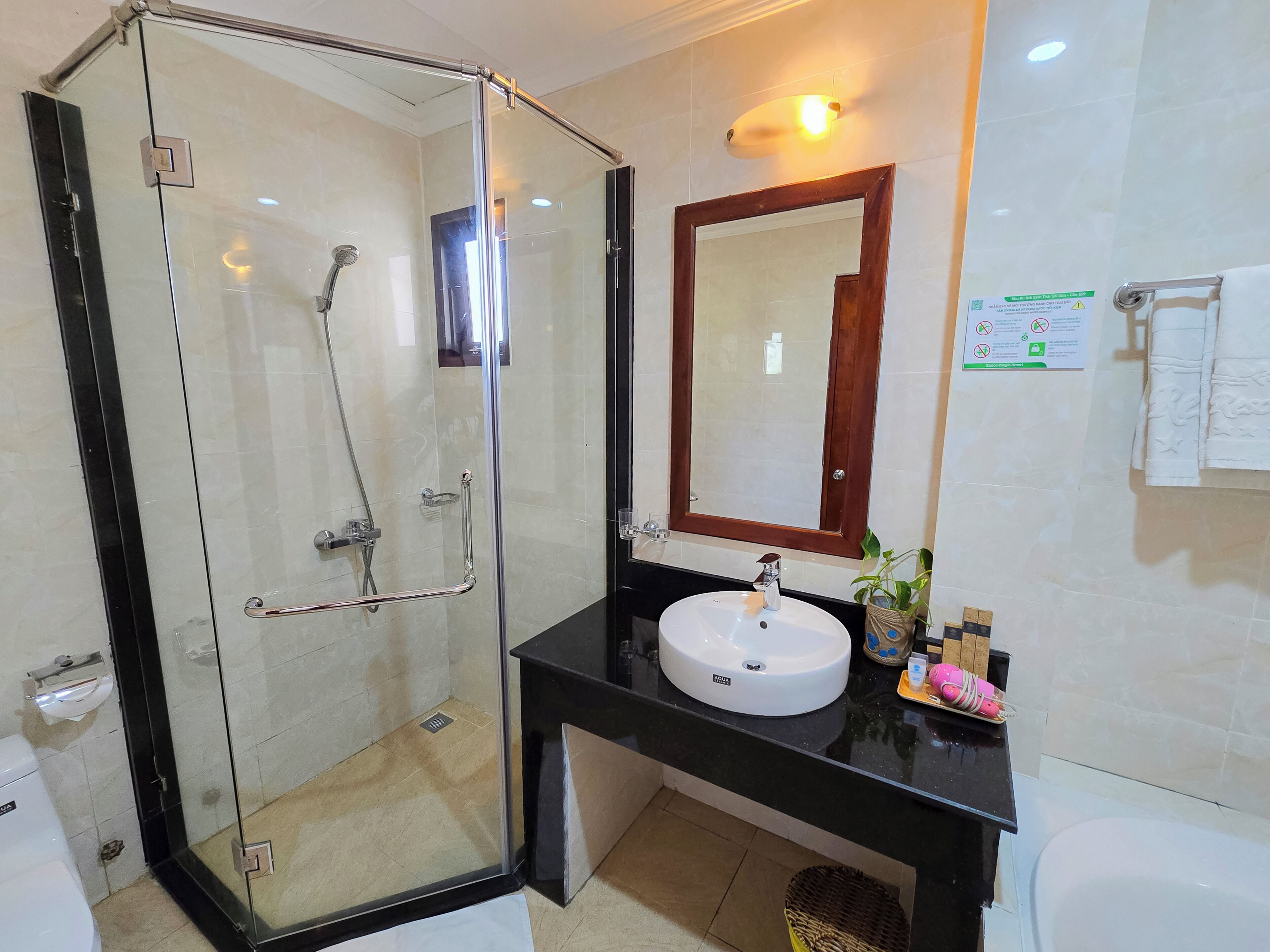 Un baño con ducha de vidrio, lavamanos con espejo y retrete.