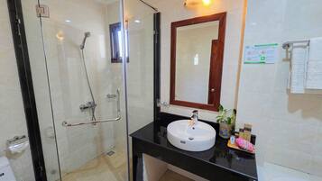 Un baño con ducha de vidrio, lavamanos con espejo y retrete.