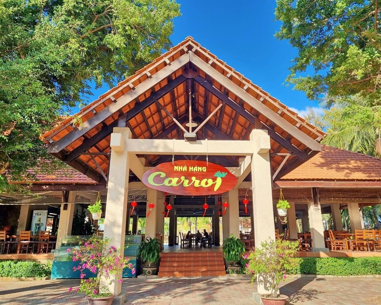 A restaurant named 'Nhà Hang Carro' with a covered outdoor seating area and potted plants.