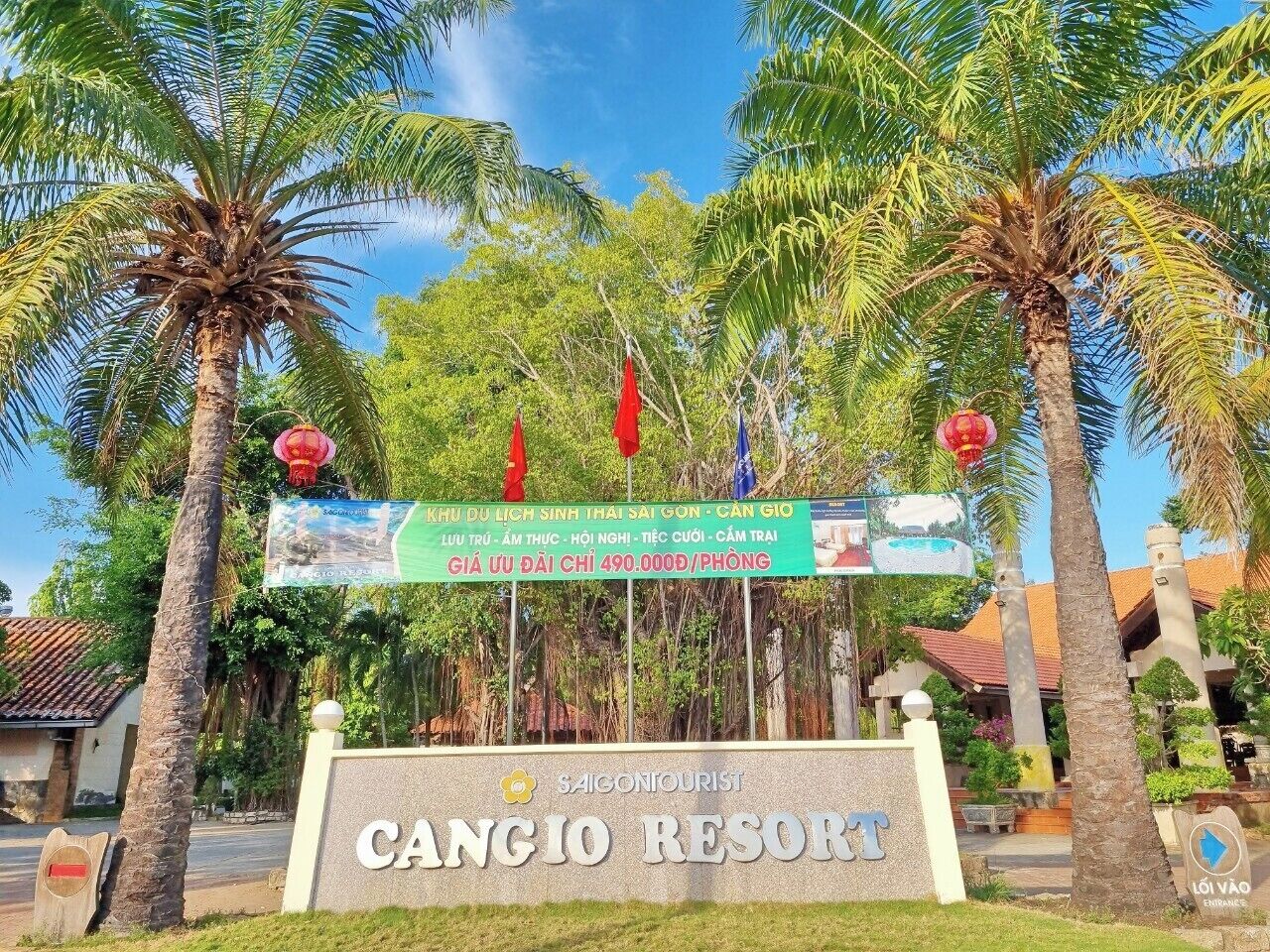 Placa para 'Cangio Resort', com vista clara da entrada, palmeiras e um edifício ao fundo.