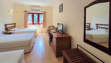 A hotel room with two beds, a desk with a computer, a mirror, and a window with curtains.