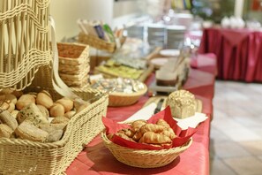 A buffet table with various food items including bread, pastries, and cheese. - Radisson Hotel Leipzig City Nord (Leipzig)