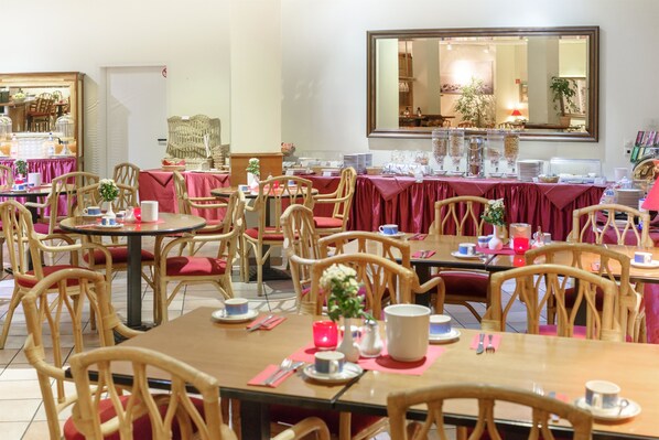 Un comedor con varias mesas y sillas, cada conjunto con vajilla y un florero.