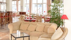 A cozy living area with a beige sofa, a glass coffee table, wicker armchairs, and a red lamp. - Hotel Leipzig City Nord by Campanile (Leipzig)