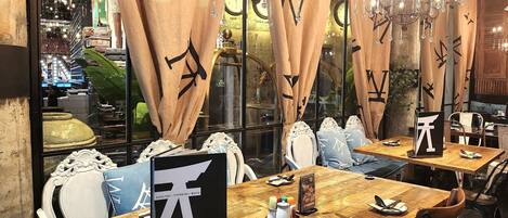 A restaurant interior with wooden tables, chairs, and a large black sign with white characters.