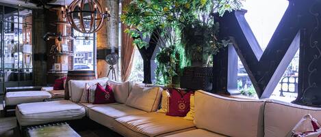 A modern interior with a large white sofa, a wooden coffee table, and a large letter 'M' structure.